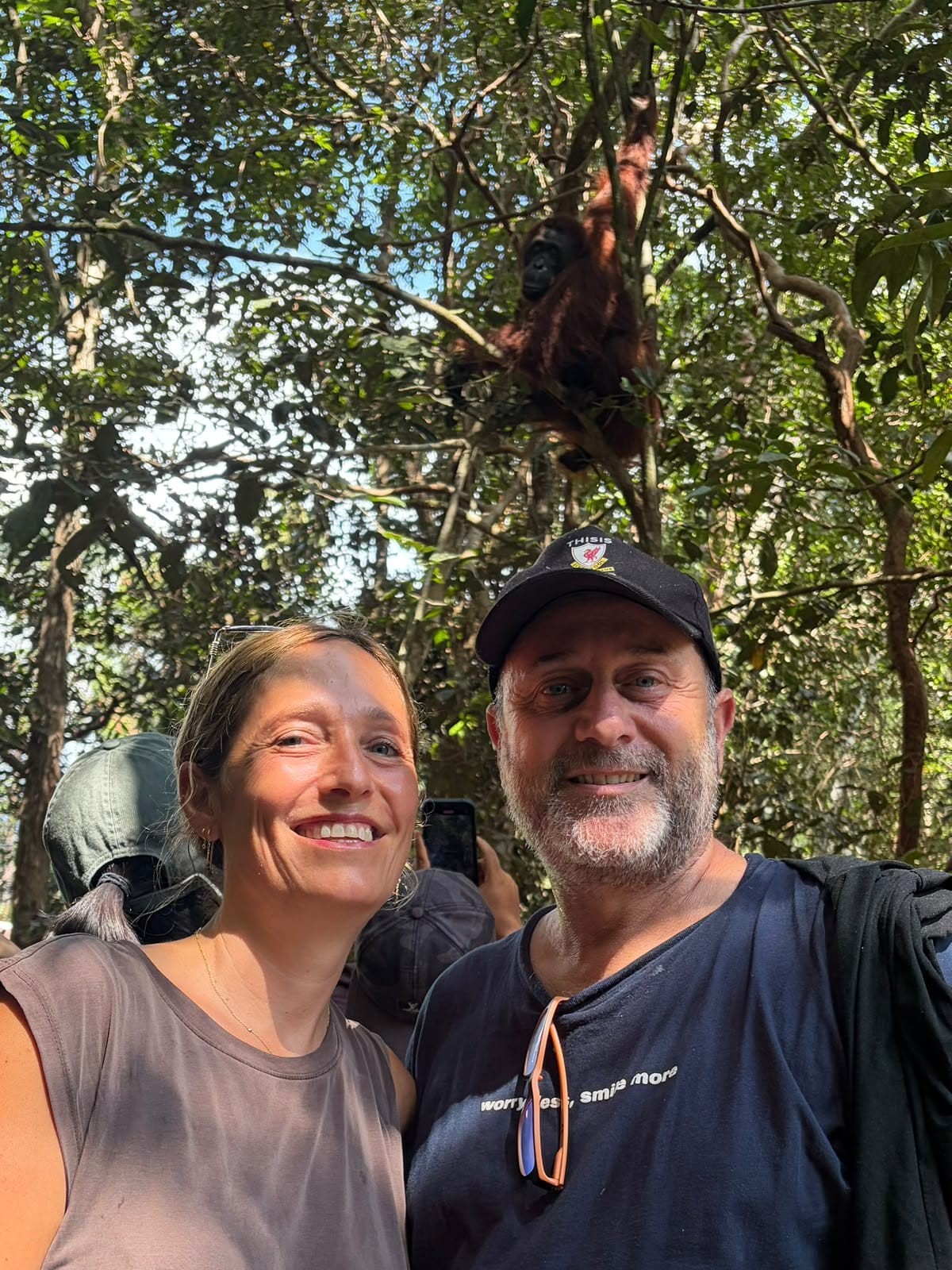 Selfie seru bersama orangutan liar yang bertengger penasaran di pohon tepat di atas.