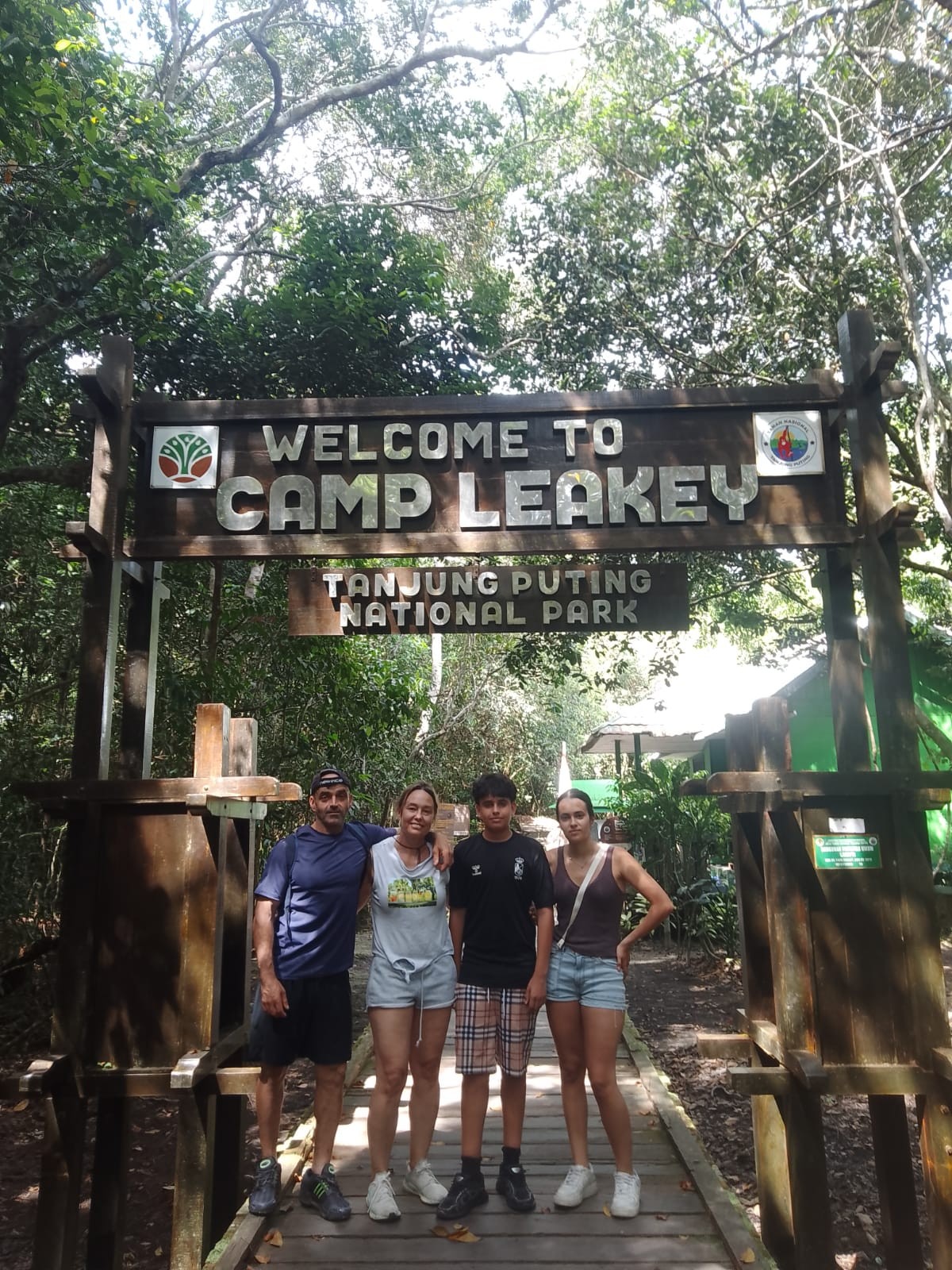 Keluarga berpose di gerbang ikonik Camp Leakey di dalam Taman Nasional Tanjung Puting.