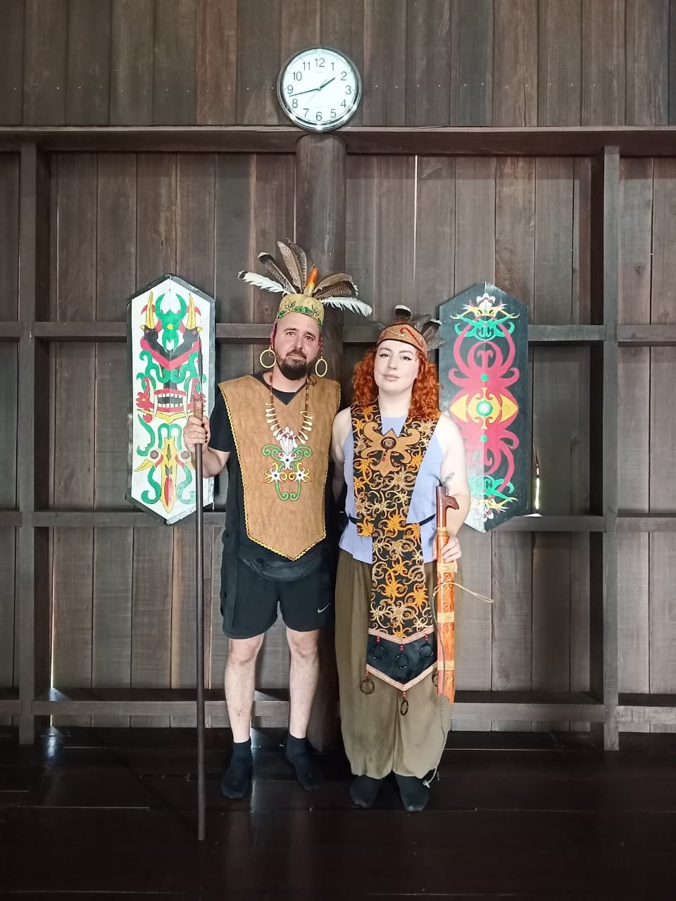 Tamu mengenakan pakaian adat pejuang dan upacara Dayak di dalam rumah betang tradisional.
